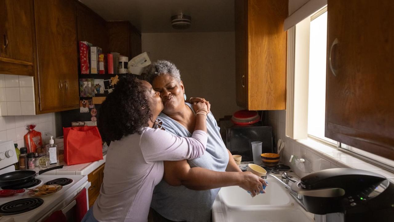 Two women hugging in a kitchen.