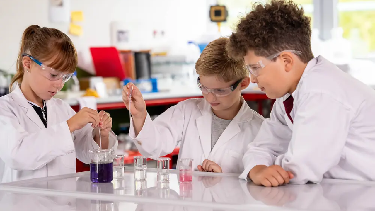 Young students in white coats doing lab experiments