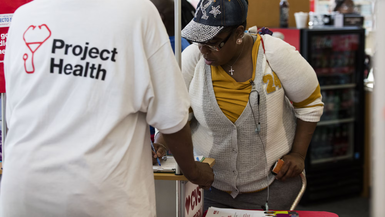 Person wearing Project Health shirt helps someone to sign up