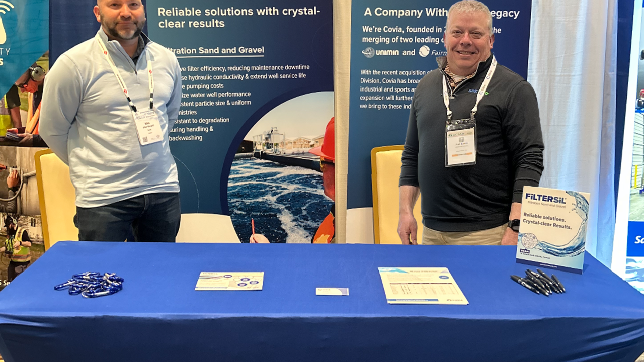 Mike Mongell and Joel Eaton standing behind a Covia desk at an event