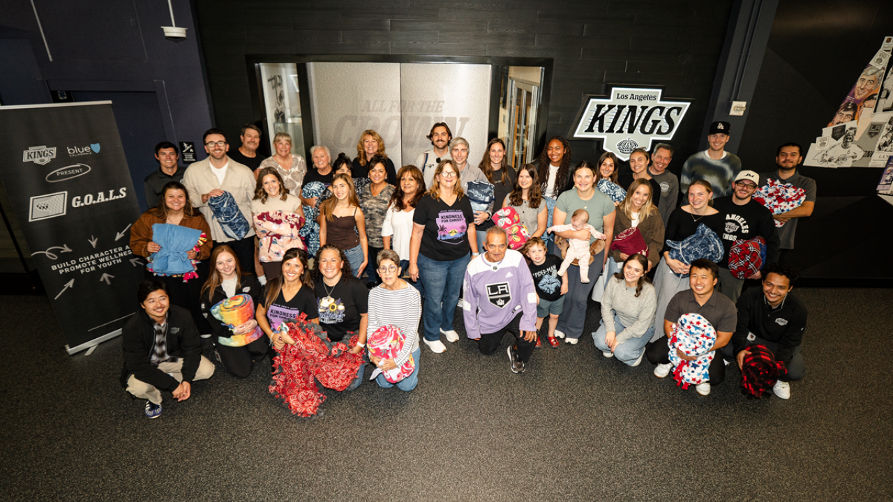 Volunteers pose for group photo in front of the Kings office with blankets made 