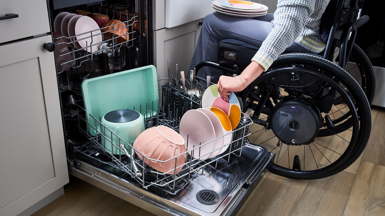 person in a wheelchair loading a diswasher