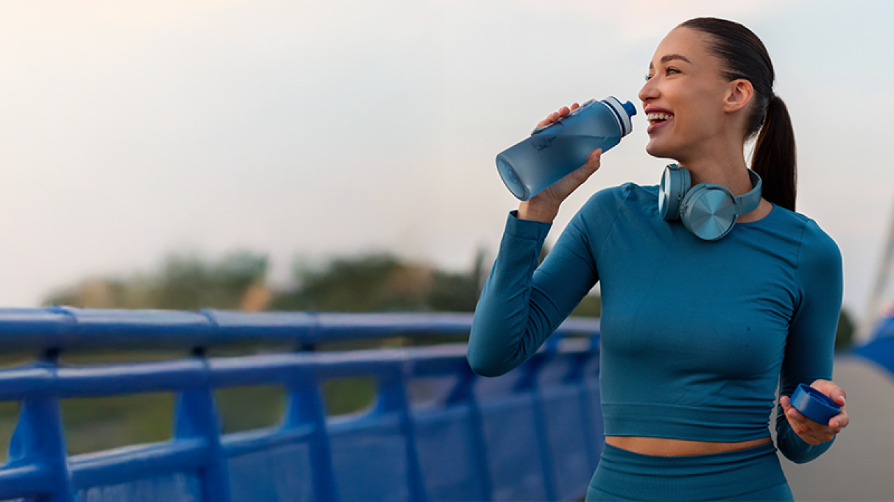 A person walking on a bridge with a water bottle.