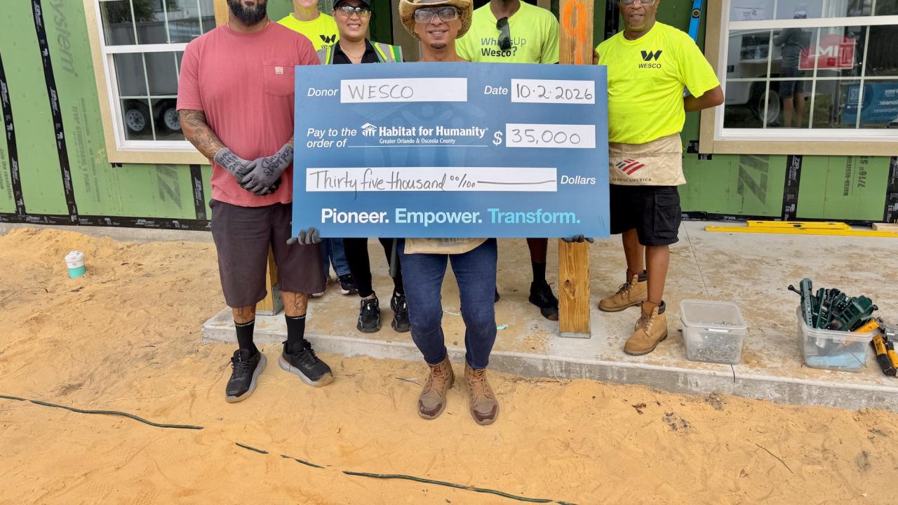 Wesco and Habitat for Humanity Team Members shown with $35,000 grant check on a building site.
