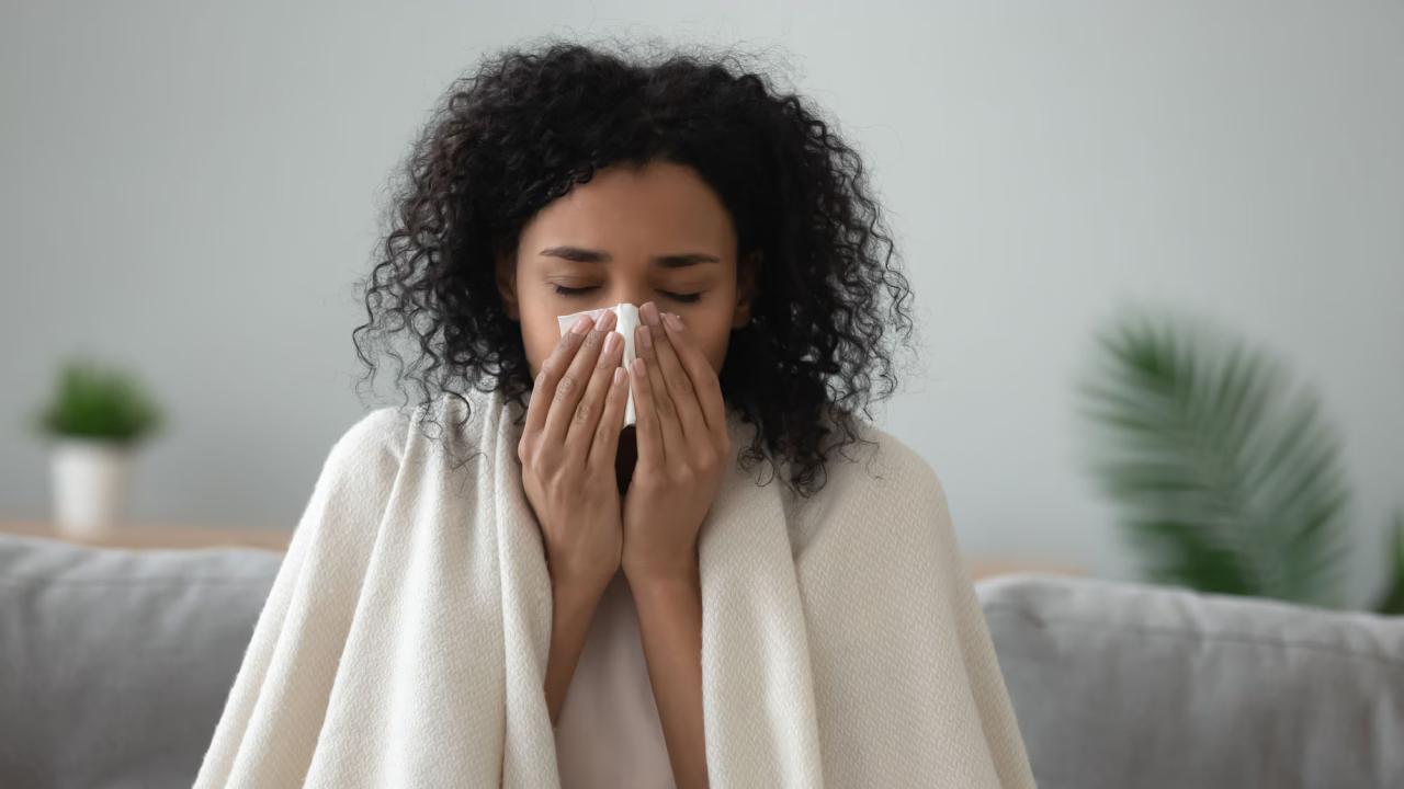 A person shown with a tissue and a blanket over their shoulders.
