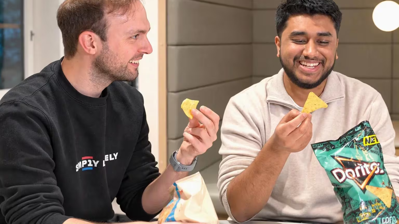 two smiling people eating Doritos