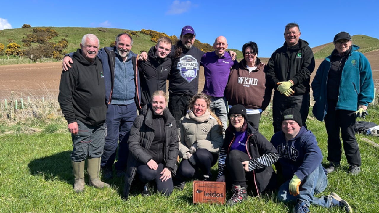 12 people posing together on a hillside